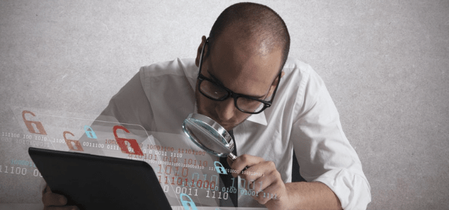 A man examines a computer with a magnifying glass